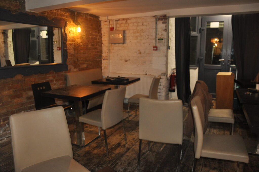 A dingy restaurant full of mismatched chairs and cold brick walls