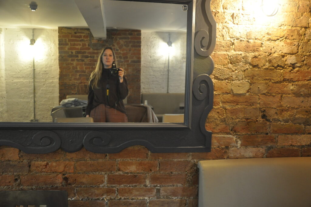Selfie in mirror attached to brick wall 